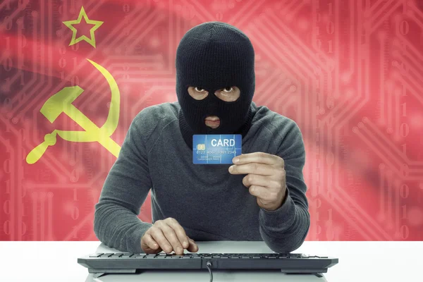 Dark-skinned hacker with flag on background holding credit card - USSR - Soviet Union