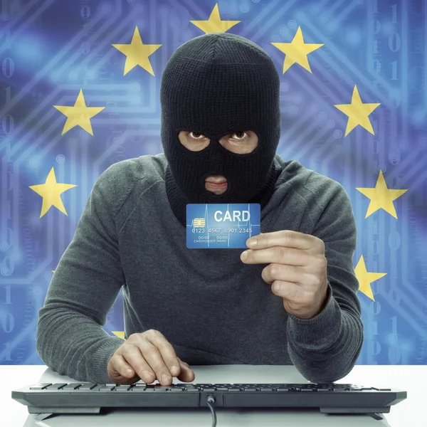 Dark-skinned hacker with flag on background holding credit card in hand - EU - European Union