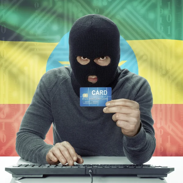 Dark-skinned hacker with flag on background holding credit card in hand - Ethiopia