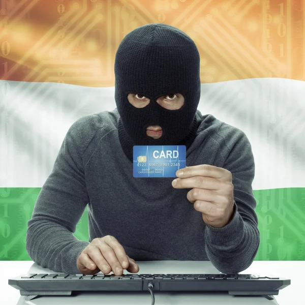 Dark-skinned hacker with flag on background holding credit card in hand - India