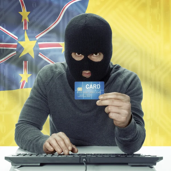 Dark-skinned hacker with flag on background holding credit card in hand - Niue