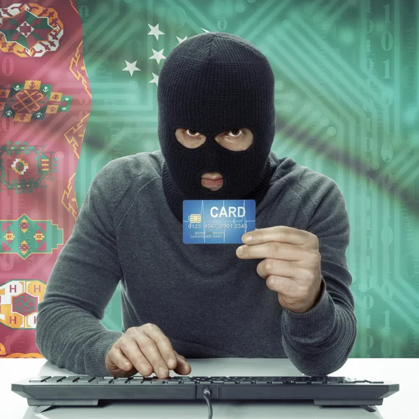 Dark-skinned hacker with flag on background holding credit card in hand - Turkmenistan
