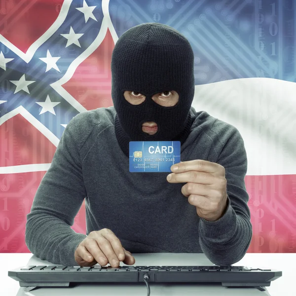 Dark-skinned hacker with USA states flag on background holding card in hand - Mississippi