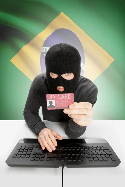 Hacker with flag on background holding ID card in hand - Brazil