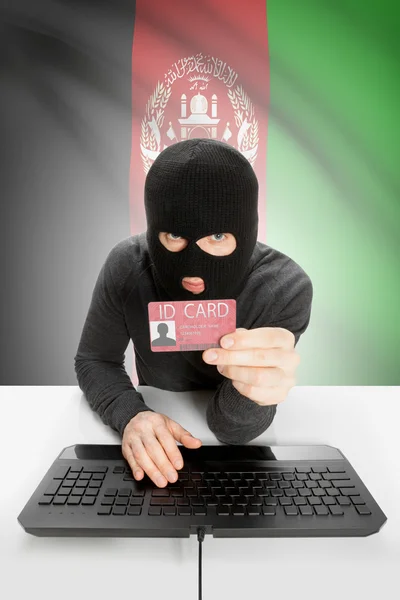 Hacker with flag on background holding ID card in hand - Afghanistan