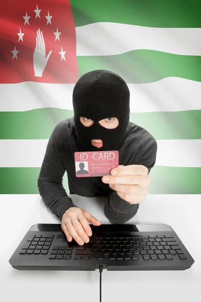 Hacker with flag on background holding ID card in hand - Abkhazia
