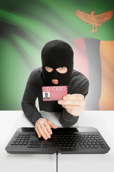 Hacker with flag on background holding ID card in hand - Zambia