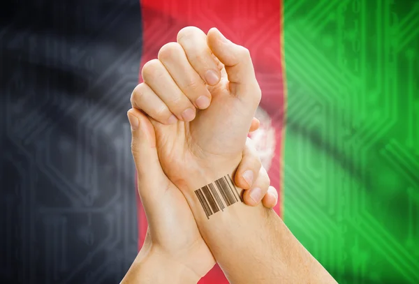 Barcode ID number on wrist and national flag on background - Afghanistan