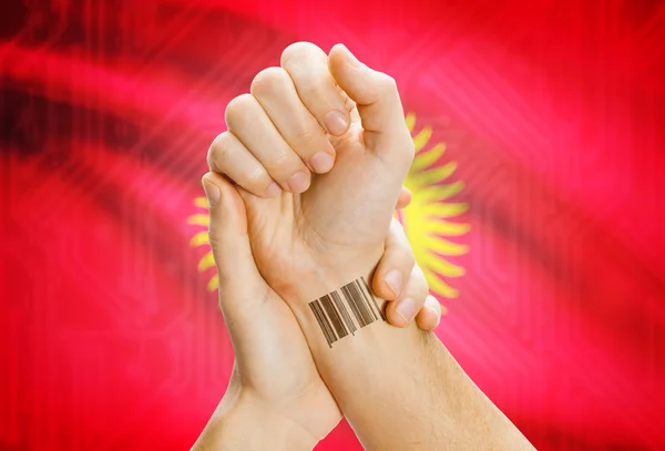 Barcode ID number on wrist and national flag on background - Kyrgyzstan
