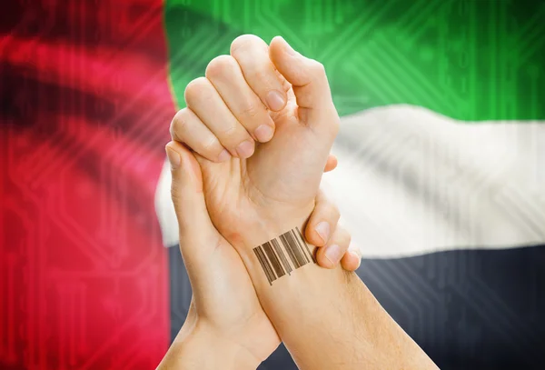 Barcode ID number on wrist and national flag on background - United Arab Emirates