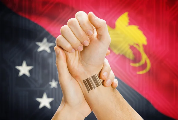 Barcode ID number on wrist and national flag on background - Papua New Guinea