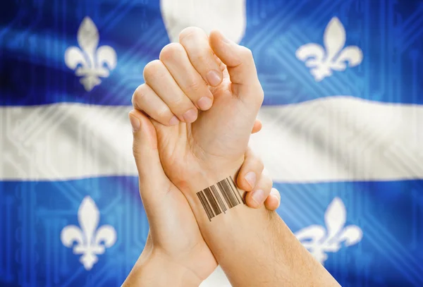 Barcode ID number on wrist with Canadian province flag on background - Quebec