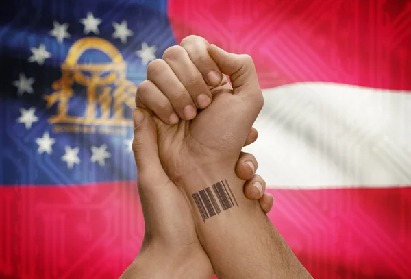 Barcode ID number on wrist of dark skinned person and USA states flags on background - Georgia
