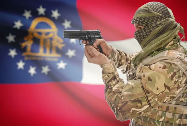 Male in muslim keffiyeh with gun in hand and flag on background - Georgia