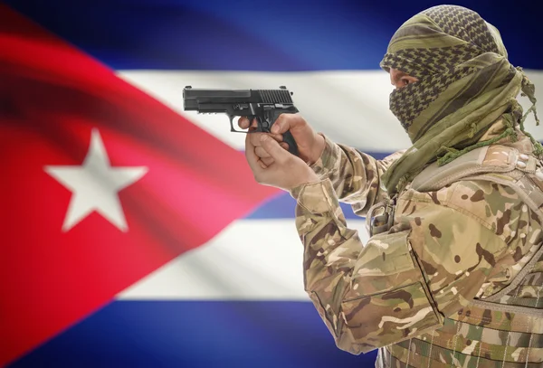 Male in muslim keffiyeh with gun in hand and national flag on background - Cuba
