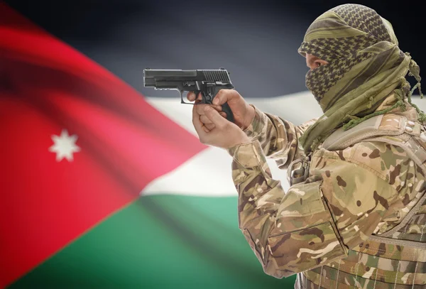 Male in muslim keffiyeh with gun in hand and national flag on background - Jordan