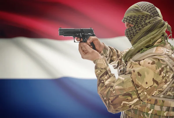 Male in muslim keffiyeh with gun in hand and national flag on background - Netherlands
