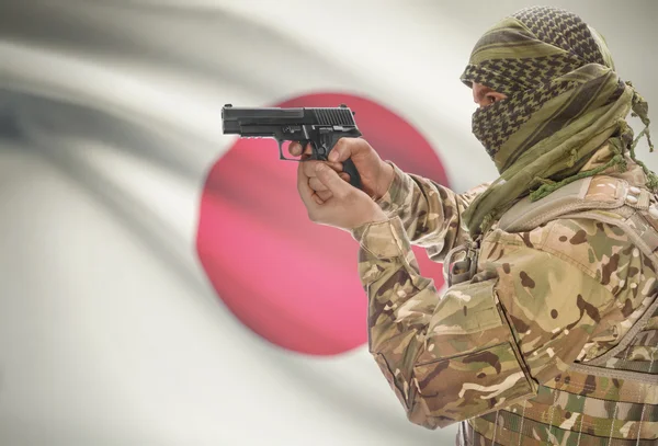 Male in muslim keffiyeh with gun in hand and national flag on background - Japan