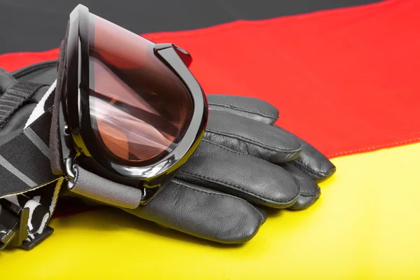 Winter sport goggles and gloves over German flag