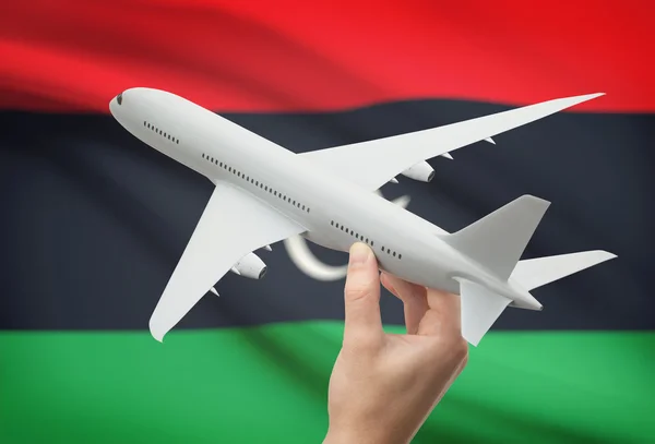 Airplane in hand with flag on background - Libya