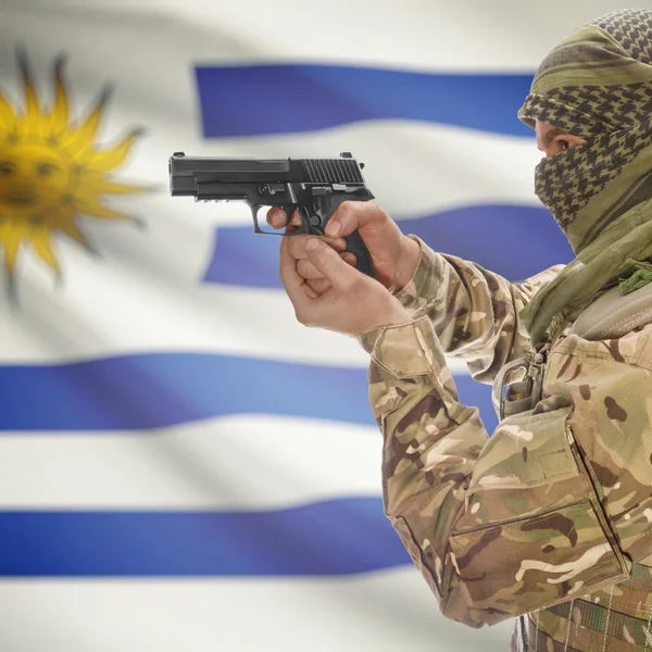 Male with gun in hands and national flag on background - Uruguay