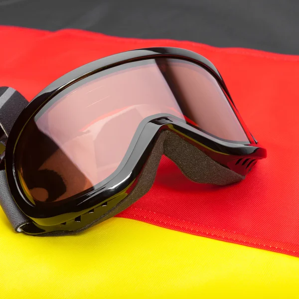Black color winter sport goggles over German flag - studio shot