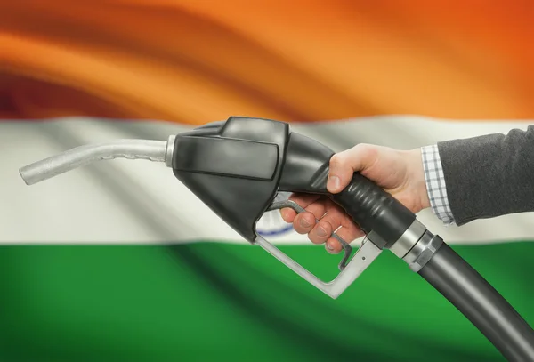 Fuel pump nozzle in hand with national flag on background - India