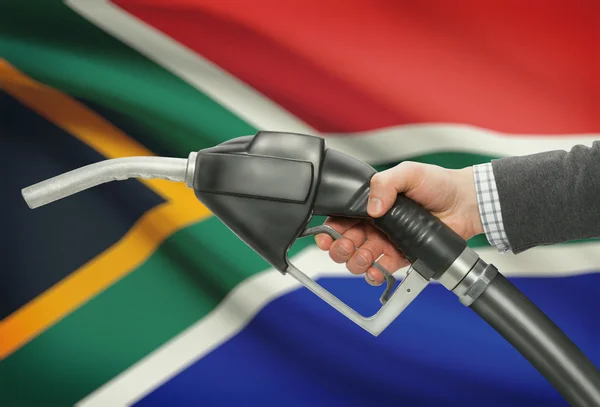 Fuel pump nozzle in hand with national flag on background - South Africa