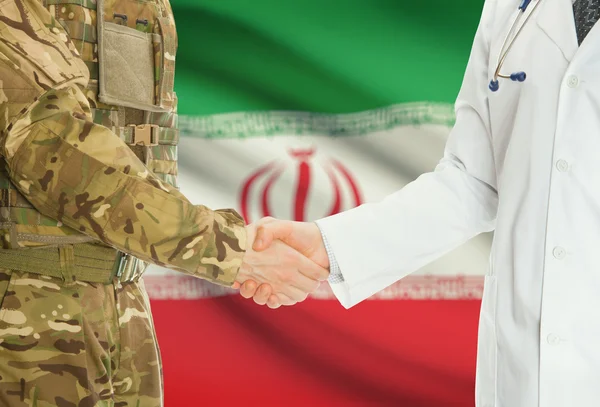 Military man in uniform and doctor shaking hands with national flag on background - Iran
