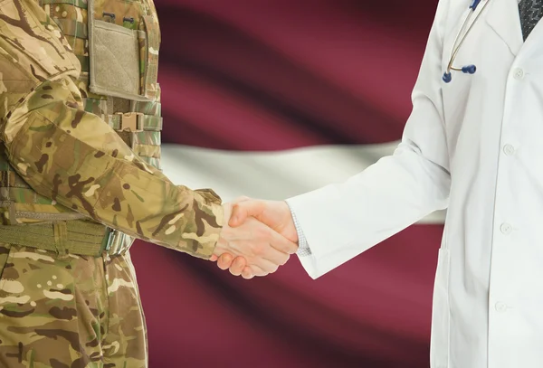 Military man in uniform and doctor shaking hands with national flag on background - Latvia