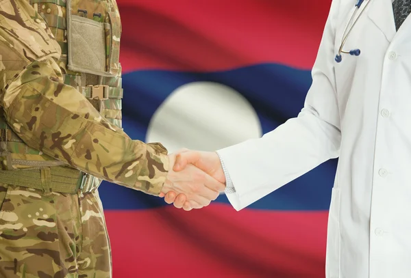 Military man in uniform and doctor shaking hands with national flag on background - Laos