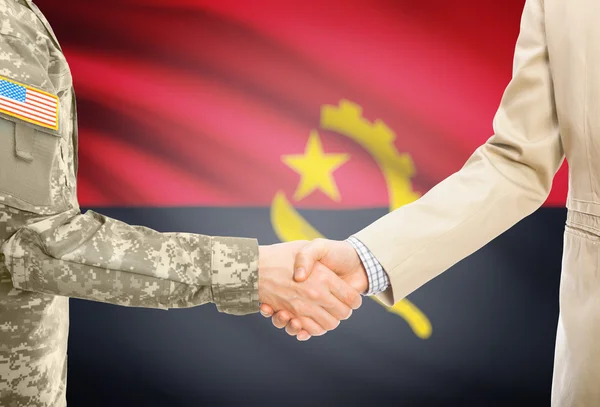 USA military man in uniform and civil man in suit shaking hands with national flag on background - Angola