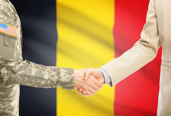 USA military man in uniform and civil man in suit shaking hands with national flag on background - Belgium