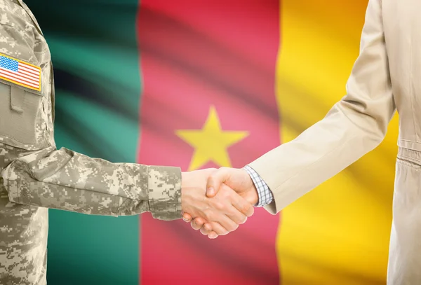 USA military man in uniform and civil man in suit shaking hands with national flag on background - Cameroon