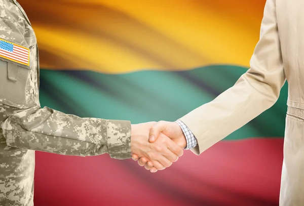 USA military man in uniform and civil man in suit shaking hands with national flag on background - Lithuania