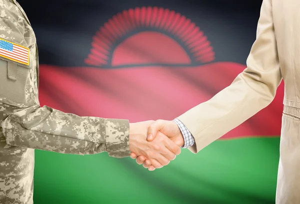 USA military man in uniform and civil man in suit shaking hands with national flag on background - Malawi