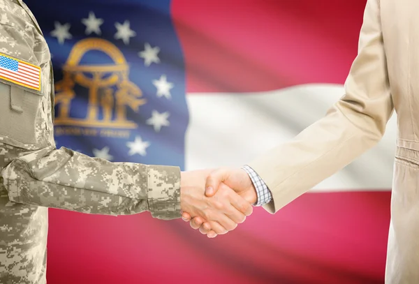 USA military man in uniform and civil man in suit shaking hands with USA state flag on background - Georgia