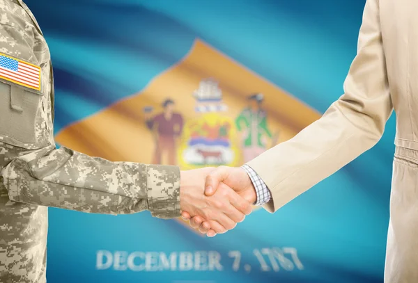 USA military man in uniform and civil man in suit shaking hands with USA state flag on background - Delaware