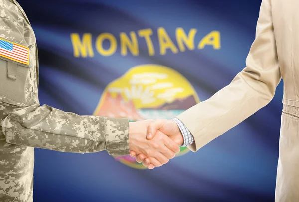 USA military man in uniform and civil man in suit shaking hands with USA state flag on background - Montana