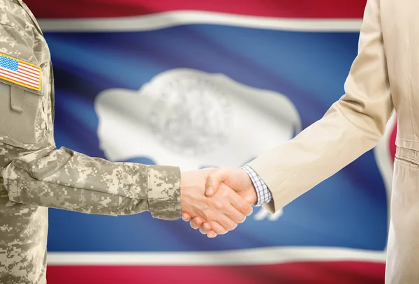 USA military man in uniform and civil man in suit shaking hands with USA state flag on background - Wyoming