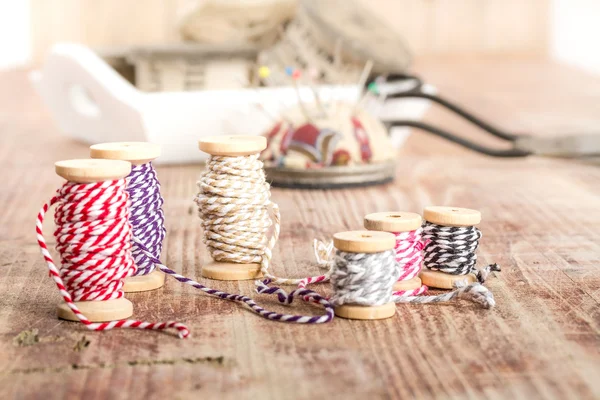 Old spools of thread, fabric, scissors on a wooden background