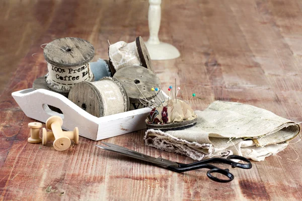 Old spools of thread, fabric, scissors on a wooden background