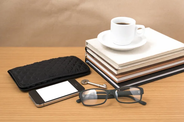 Coffee and phone with stack of book,key,eyeglasses and wallet