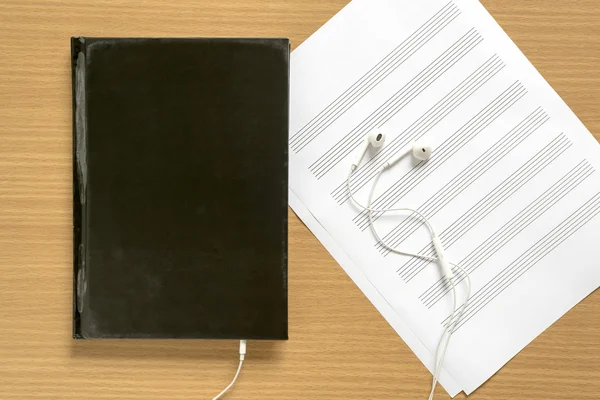 Top view of music staff paper and notebook with earphone