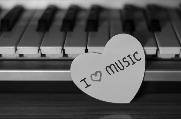 Paper heart on piano keyboard black and white