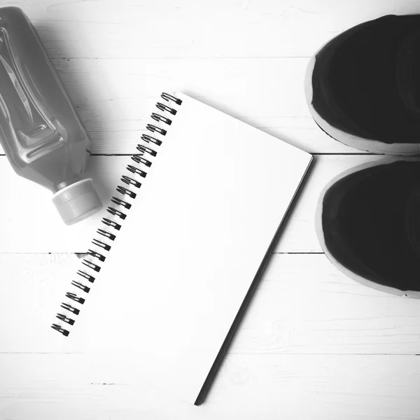 Running shoes,orange juice and notepad black and white tone colo