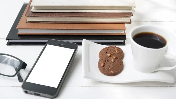 Coffee cup with cookie,phone,stack of book and eyeglasses