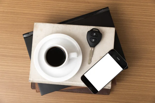 Coffee cup with phone car key and stack of book