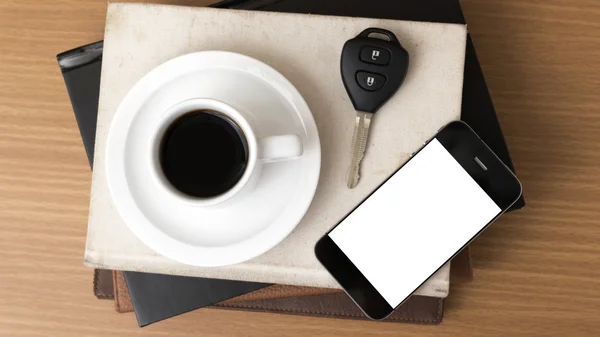 Coffee cup with phone car key and stack of book