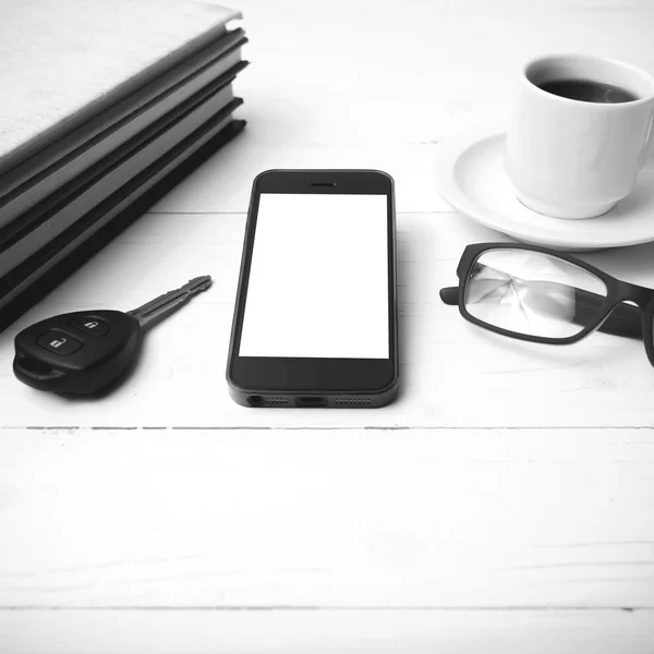 Coffee cup with phone, car key,eyeglasses and stack of book blac